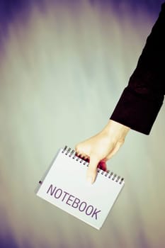 Close_up of a personŽs hand holding a spiral notebook