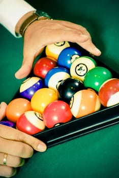 Close_up of a personŽs hands racking up pool balls on a pool table