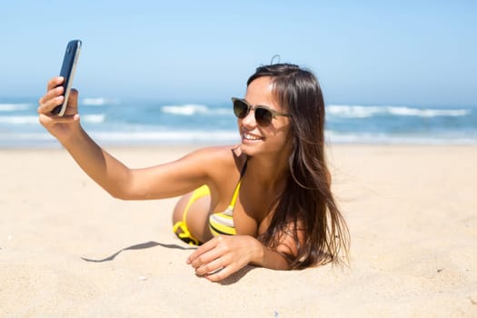 Young woman taking a selfie while relaxing at the beach