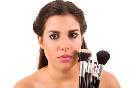 Portrait of a young and beautiful makeup artist with brushes