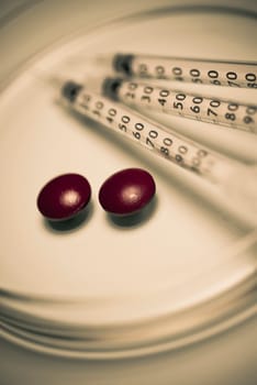 Close_up of syringes and pills on plates