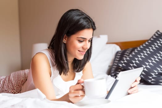 Young woman relaxing with her computer in bed