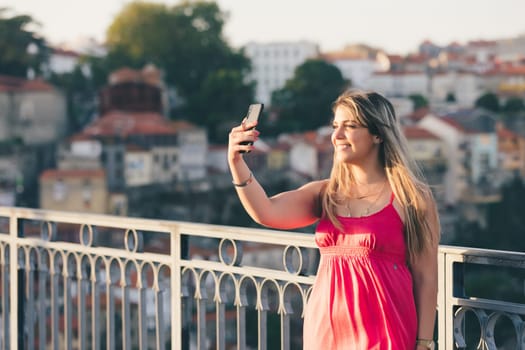Young woman tourist enjoying beautiful landscape view on the old town with river and famous iron bridge during the sunset in Porto city, Portugal