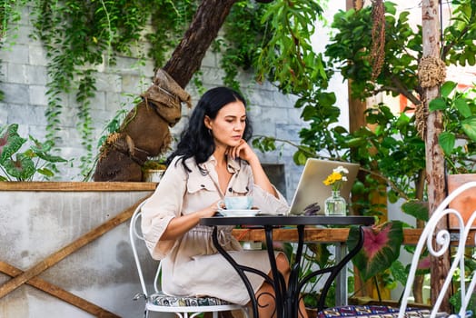 Young ukrainian brunette woman freelancer working with laptop and drinking coffee in cafe