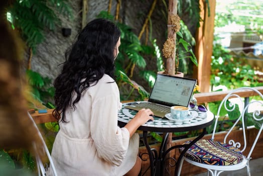 Young ukrainian brunette woman freelancer working with laptop and drinking coffee in cafe