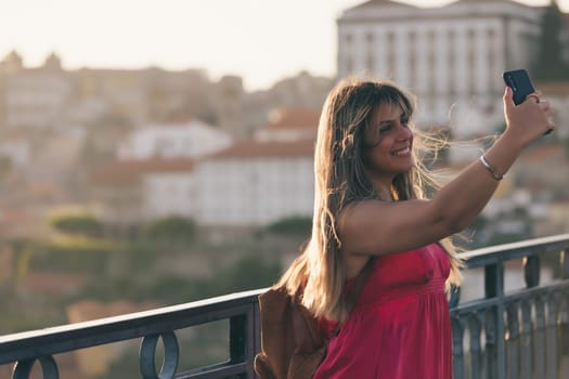 Young woman tourist enjoying beautiful landscape view on the old town with river and famous iron bridge during the sunset in Porto city, Portugal