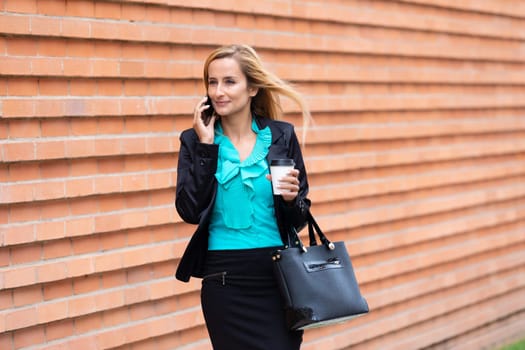 Business woman with coffe and talking on the phone near office