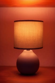 Lit lamp on a shelf in moody light