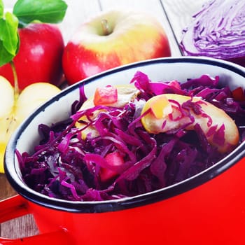 Close up Healthy Fresh Red Cabbage and Apple Salad on a Red Pot.