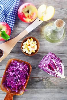 Close up Fresh Cabbage and Apple Salad Ingredients on Wooden Table with a Bottle of Vinegar.