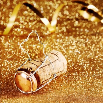 Festive Decoration Concept - Close up Wooden Wine Cork with Cage on Golden Particles with Paper Streamers.