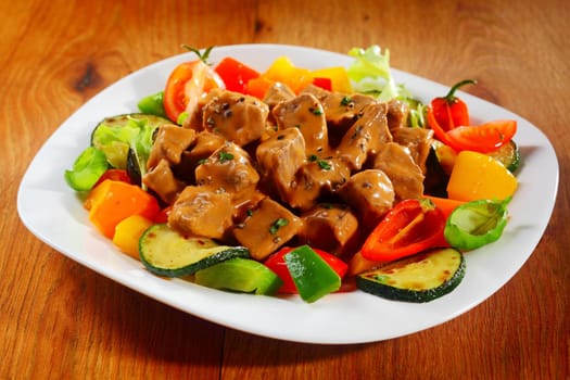 Close up Gourmet Appetizing Saucy Meat Slices with Spices on a Plate on Top of Brown Wooden Table.
