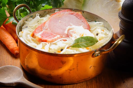 Close up Smoked Pork Chop Meat on Shredded Cabbage with Raisins Inside a Golden Cooking Pot