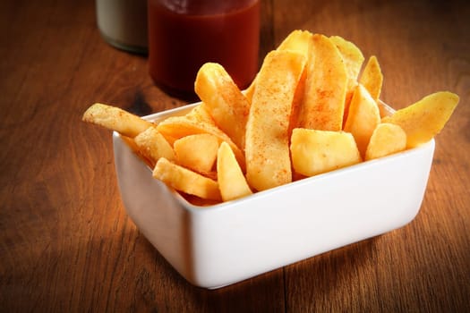 Close up Crispy Potato French Fries on White Plate on Wooden Table
