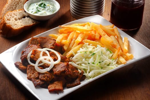 Close up Tasty Gyros, Shredded Cabbage and Potato French Fries on White Plate, Placed on Wooden Table.
