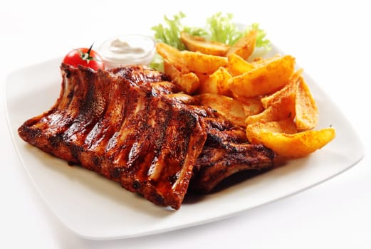 Close up Gourmet Grilled Pork Rib and Fried Potato Wedges on White Plate with Sauce and Veggies, Isolated on White Background.