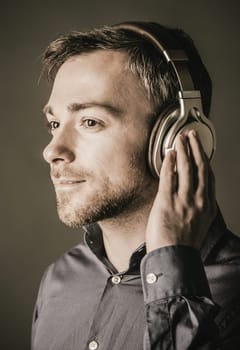 Young man listening to music on stereo headphones with a quiet smile and dreamy expression of appreciation