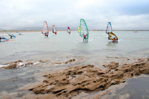wind surfers racing in the storm winds on the wild atlantic way in county Kerry Ireland near rocks