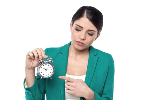 Sad corporate woman pointing alarm clock