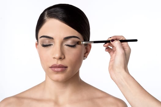 Woman applying shadow powder on eyes with brush