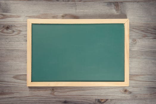 Empty blank green chalkboard with wooden frame on old wood background