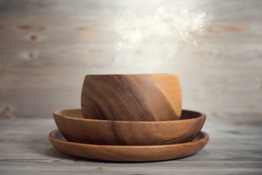 Empty bowl with hot smoke on old wooden table. Dramatic light.