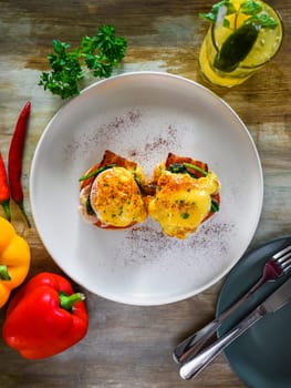 English muffin with poached eggs, bacon and Hollandaise sauce with vegetables