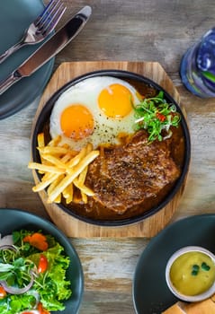 Vietnamese beef steak with french fries, fried eggs, baguette, served with lemonade drink, vegetable salad