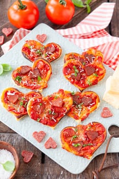 Little pizza in hearts shapes with sausage and cheese