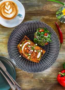 Smashed avocado with poached eggs, red pepper pesto and pickle shallot on toast top view