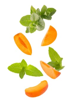 Isolated fruits and herbs. Seven flying peppermint leaves and apricot slices on white with clipping path as package design element. Full depth of field. Food levitation concept.