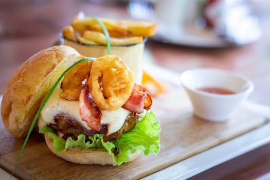 Tasty beef hamburger, with calamares, salad, bacon and egg and french fries. Selective focus.