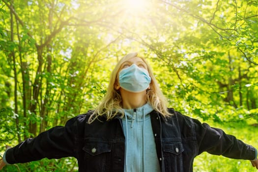 Young woman in medical face protection mask outdoors in nature. Girl hoping for the end to the pandemic.