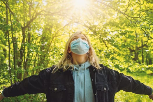 Young woman in medical face protection mask outdoors in nature. Girl hoping for the end to the pandemic.