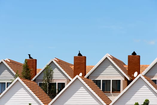 Close up detail of town house rooftops with chimneys against blue shy.