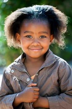 Outdoor portrait of cute African girl wearing brown jacket.