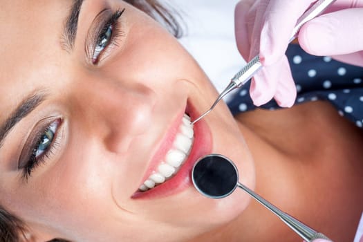 Macro close up of Dentist hands working attractive female teeth.