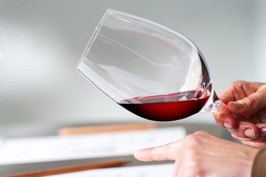 Close up of Hands testing wine density in wine glass at tasting.