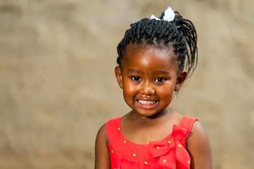 Close up portrait of little african girl with braided hair outdoors.
