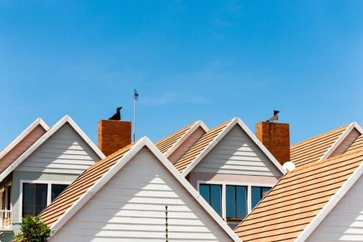 Close up detail of complex house rooftops against blue sky.