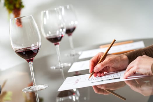 Close up of female hands writing notes at wine tasting.