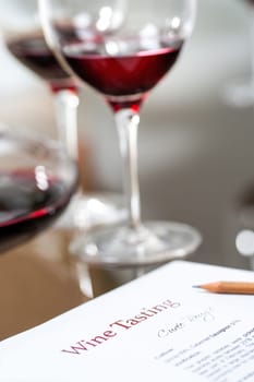 Macro close up of red wine information sheet and red wine glasses at wine tasting.