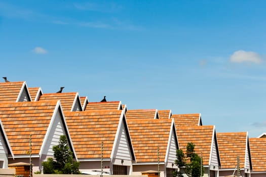 Row of condominium rooftops against blue sky.