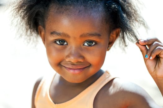 Close up face shot of cute African girl touching hair.