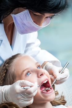 Close up portrait Female Dentist working on little girls teeth.