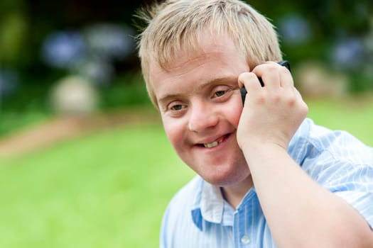 Close up portrait of handicapped boy talking on smart phone outdoors.