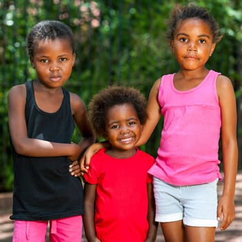 Portrait of three cute young african girls standing together outdoors.