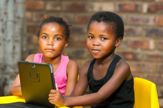 Close up portrait of two african kids with digital tablet outdoors.