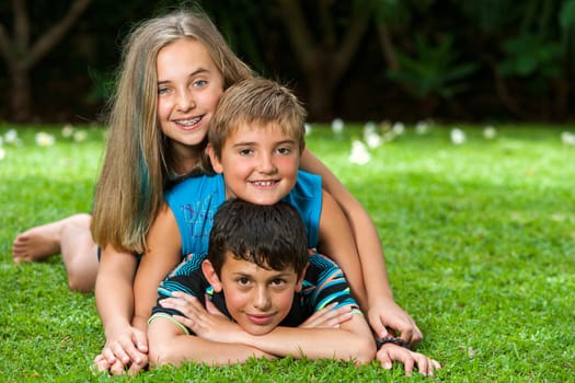 Portrait of kids paking human pile outdoors on grass.