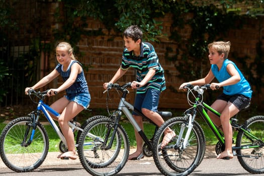 Motion shot of three kidscompeting with cycles outdoors.